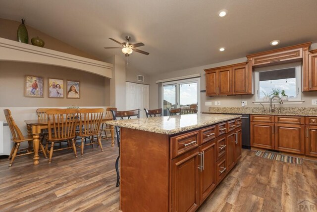 kitchen featuring vaulted ceiling, brown cabinets, a kitchen island, and a kitchen breakfast bar