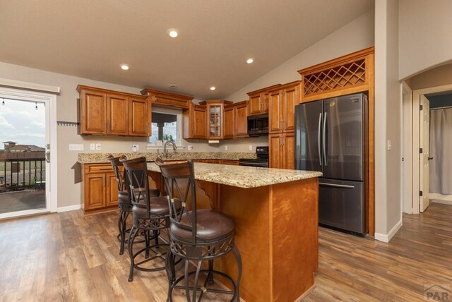 kitchen featuring a kitchen island, glass insert cabinets, freestanding refrigerator, vaulted ceiling, and black electric range