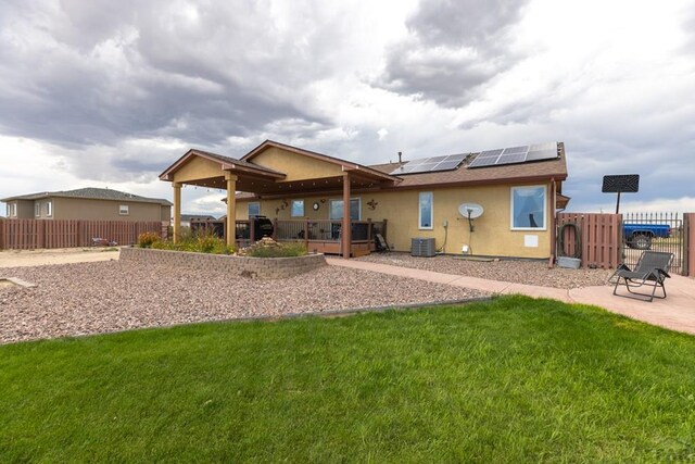 rear view of property with a patio, a fenced backyard, solar panels, a yard, and stucco siding