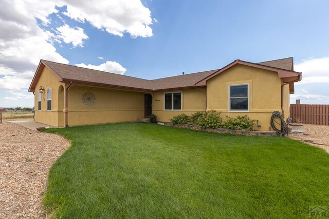 view of front of property featuring fence, a front lawn, and stucco siding