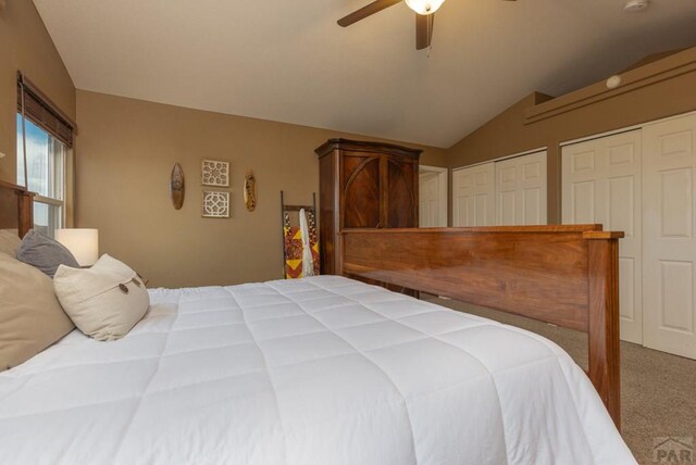 carpeted bedroom featuring vaulted ceiling, ceiling fan, and two closets