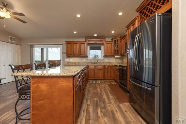 kitchen with a kitchen island, visible vents, a kitchen breakfast bar, freestanding refrigerator, and brown cabinetry