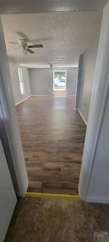 605 E 8th St, La Junta, CO 81050 - hallway featuring wood finished floors, baseboards, and a textured ceiling