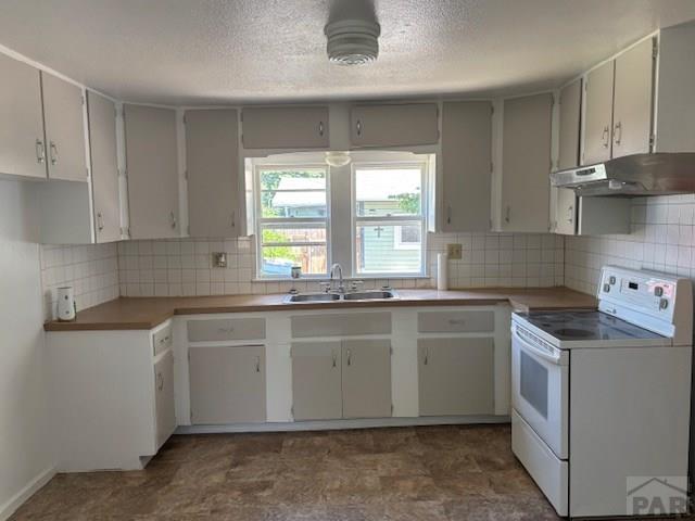 605 E 8th St, La Junta, CO 81050 - kitchen with electric range, a sink, under cabinet range hood, a textured ceiling, and decorative backsplash