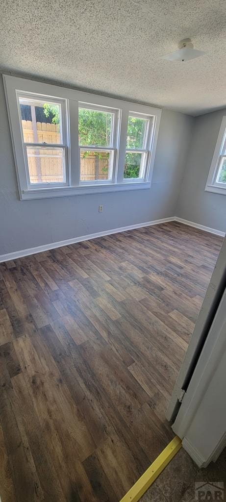 605 E 8th St, La Junta, CO 81050 - unfurnished room featuring dark wood-style floors, a textured ceiling, and baseboards