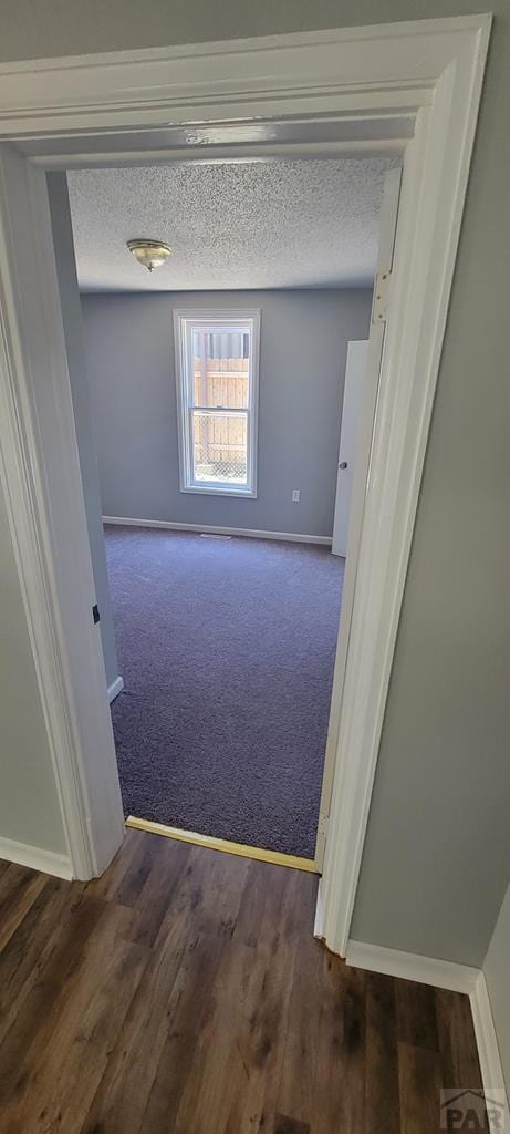 605 E 8th St, La Junta, CO 81050 - unfurnished room featuring baseboards, dark carpet, and a textured ceiling