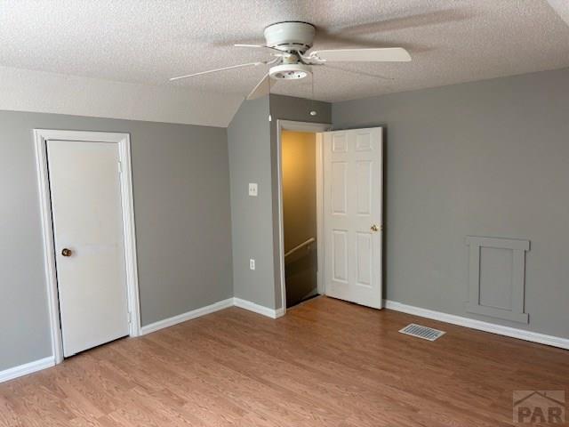 605 E 8th St, La Junta, CO 81050 - unfurnished bedroom featuring light wood-style floors, baseboards, a textured ceiling, and a ceiling fan