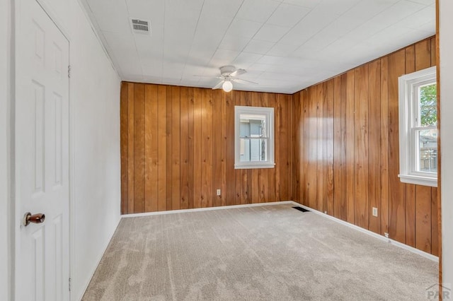 carpeted empty room featuring a ceiling fan, visible vents, and baseboards