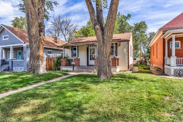 view of front of home featuring a porch, fence, a front lawn, and stucco siding