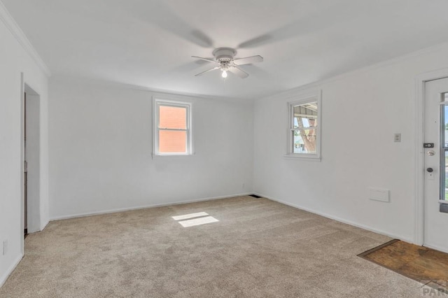 unfurnished room with a ceiling fan, light carpet, ornamental molding, and baseboards