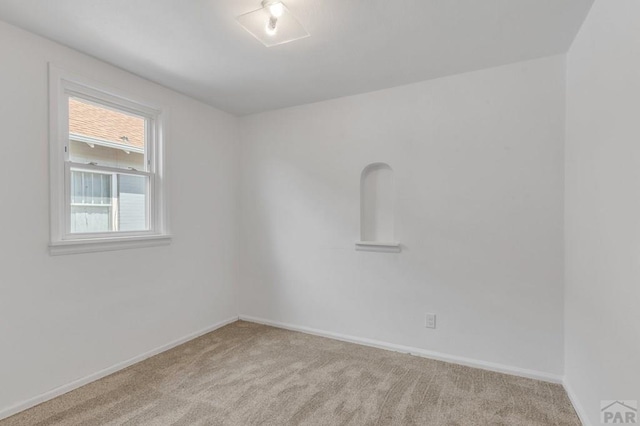 spare room with light colored carpet and baseboards