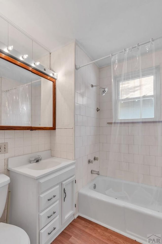 full bath with tile walls, toilet, shower / tub combo, vanity, and wood finished floors