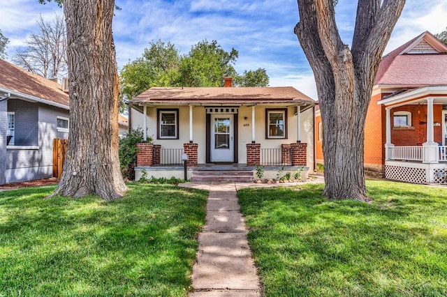 view of front of property featuring covered porch, a chimney, a front yard, and stucco siding