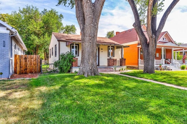 view of front of house featuring a porch, fence, and a front lawn