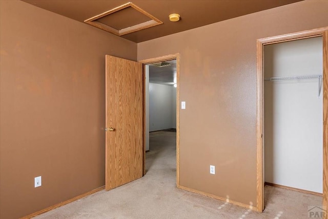 unfurnished bedroom featuring light carpet, attic access, baseboards, and a closet