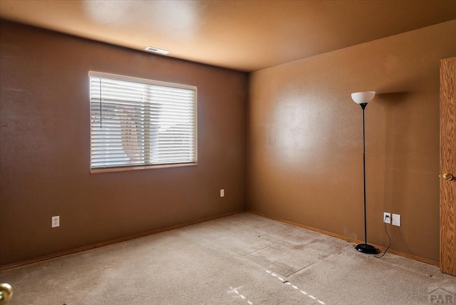 empty room featuring visible vents and light colored carpet