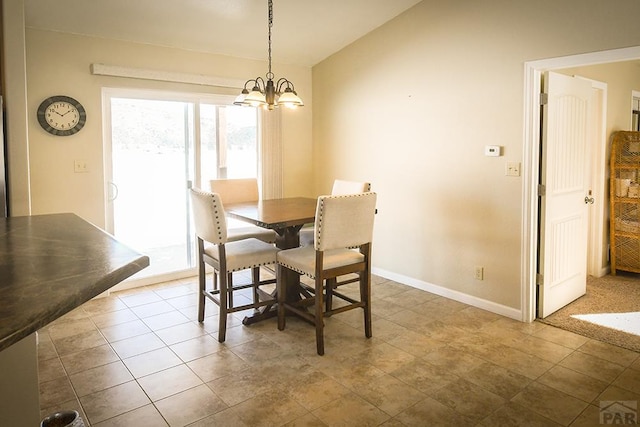 tiled dining space featuring a chandelier, vaulted ceiling, and baseboards