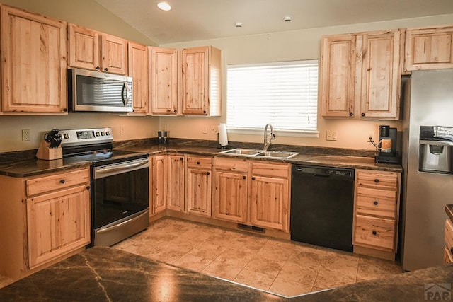 kitchen with dark countertops, vaulted ceiling, stainless steel appliances, and a sink