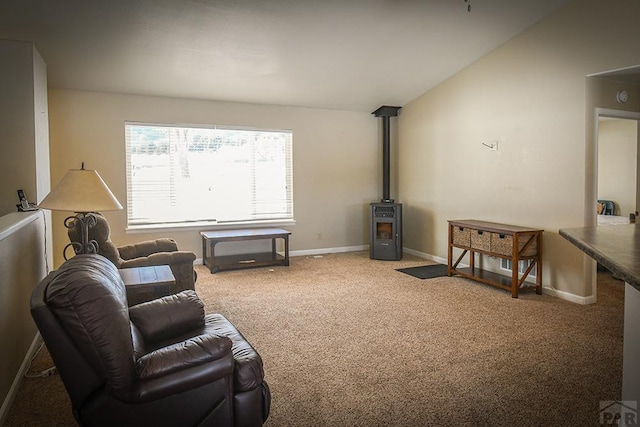 carpeted living area with a wood stove, vaulted ceiling, and baseboards