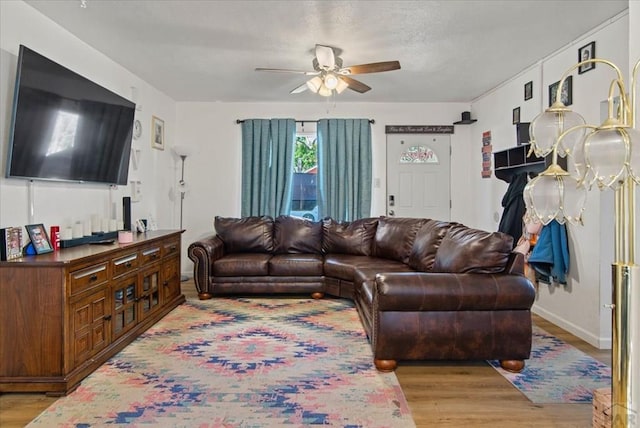 living area featuring light wood-type flooring, ceiling fan, and baseboards