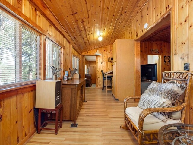 living area with lofted ceiling, wood ceiling, wood walls, and light wood finished floors