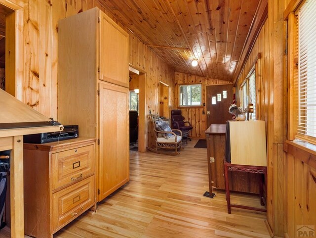 kitchen with wooden walls, lofted ceiling, wood ceiling, light wood-style flooring, and light brown cabinets