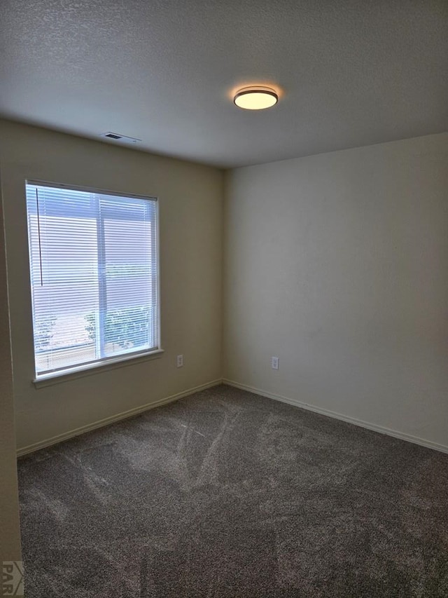 empty room featuring baseboards, carpet, visible vents, and a textured ceiling