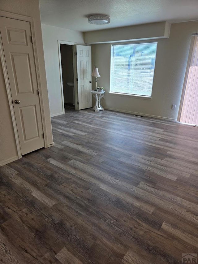 interior space featuring baseboards and dark wood-type flooring