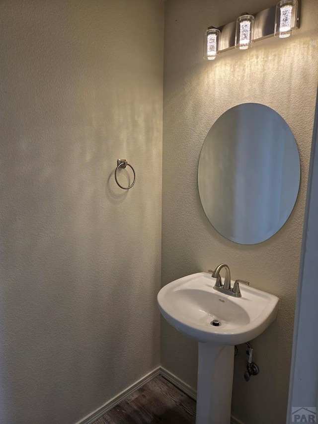 bathroom featuring baseboards, wood finished floors, and a textured wall