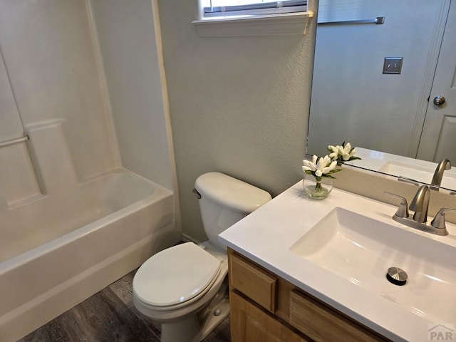 bathroom with a textured wall, vanity, toilet, and wood finished floors