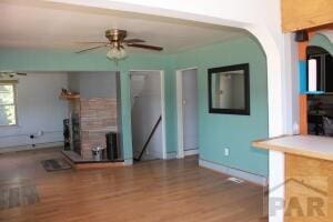 unfurnished living room with ceiling fan, baseboards, and wood finished floors