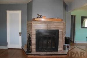 interior details with baseboards, a tiled fireplace, and wood finished floors