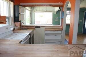 kitchen featuring arched walkways, a sink, and white electric range oven