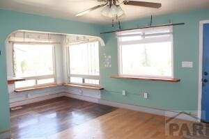 spare room featuring a healthy amount of sunlight, baseboards, a ceiling fan, and wood finished floors