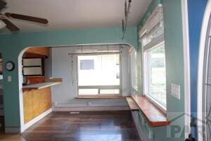 unfurnished dining area with dark wood-type flooring, track lighting, and a ceiling fan