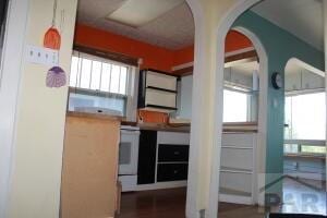 kitchen featuring arched walkways and white range with electric stovetop