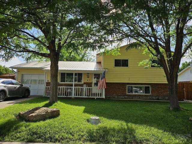 split level home featuring a garage, a front lawn, covered porch, and brick siding