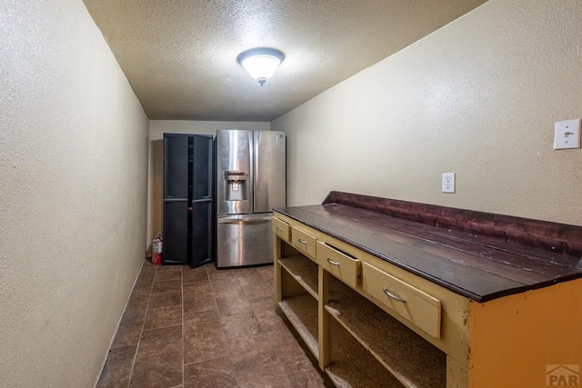 318 E Goddard Ave, Trinidad, CO 81082 - kitchen featuring stainless steel refrigerator with ice dispenser, dark countertops, a textured wall, a textured ceiling, and open shelves