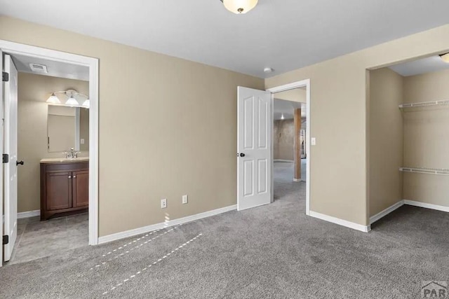 unfurnished bedroom featuring light carpet, visible vents, baseboards, ensuite bath, and a closet