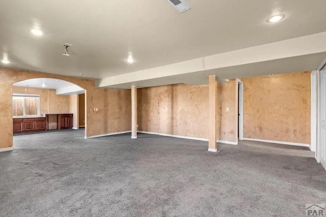 basement featuring arched walkways, recessed lighting, visible vents, baseboards, and dark colored carpet