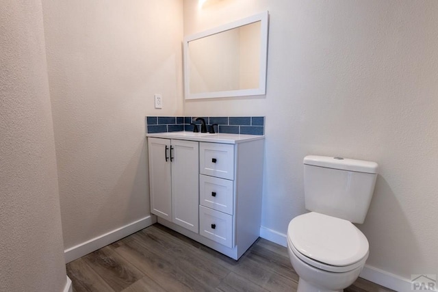 bathroom featuring toilet, wood finished floors, vanity, and baseboards