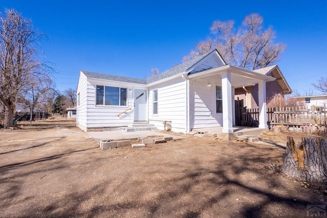 bungalow-style home with entry steps, roof with shingles, and fence