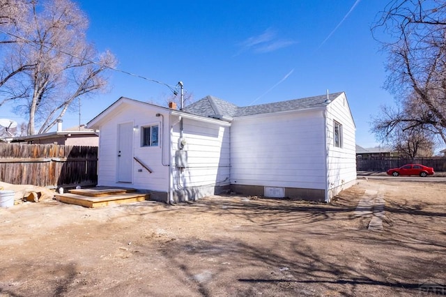 rear view of property with roof with shingles and fence