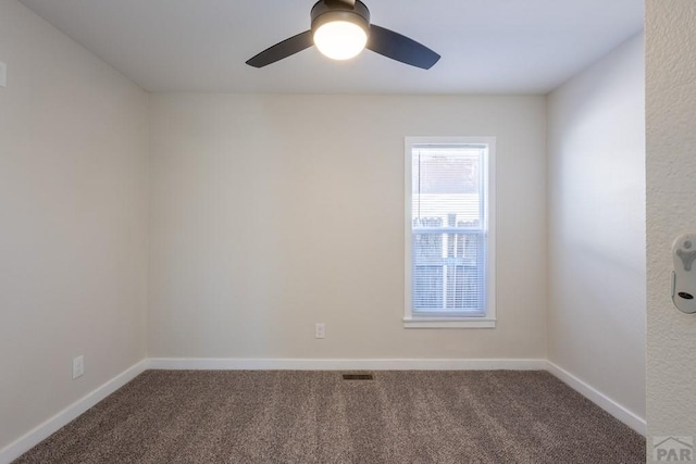 carpeted spare room featuring a ceiling fan, visible vents, and baseboards