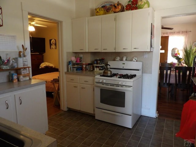 1724 E Abriendo Ave, Pueblo, CO 81004 - kitchen with white range with gas cooktop, a ceiling fan, white cabinetry, and dark tile patterned flooring