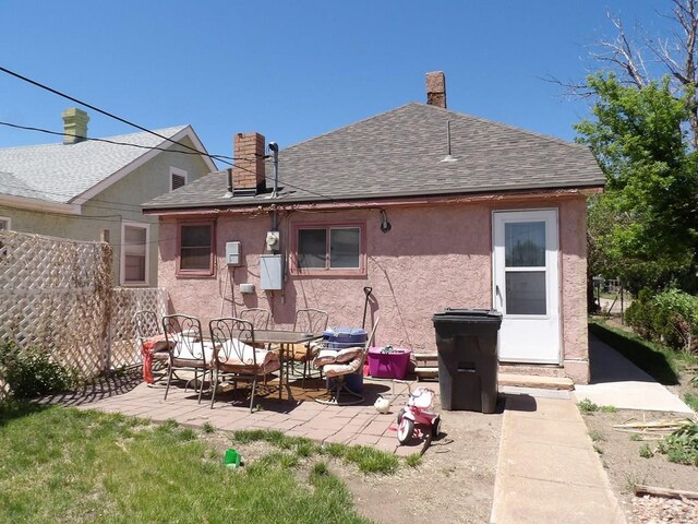 1724 E Abriendo Ave, Pueblo, CO 81004 - back of house with a shingled roof, stucco siding, a patio, and a chimney