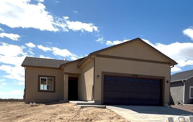 single story home with an attached garage, stucco siding, and driveway