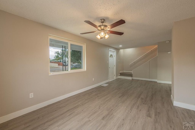 interior space with visible vents, a ceiling fan, a textured ceiling, wood finished floors, and baseboards