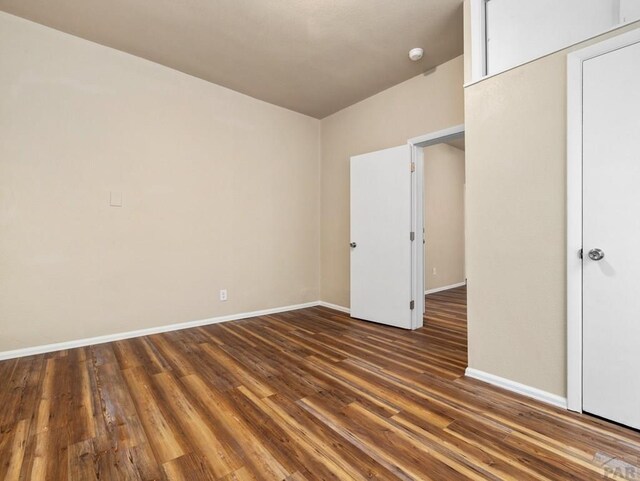 unfurnished bedroom with dark wood-type flooring and baseboards