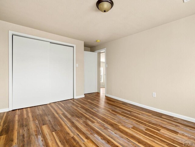 unfurnished bedroom with a closet, baseboards, and wood finished floors